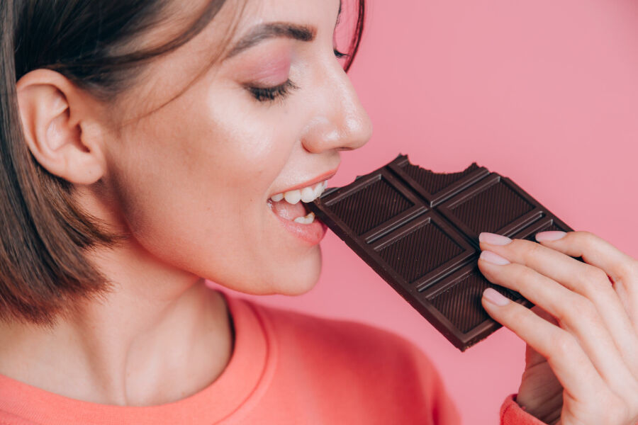 Imagem beautiful-young-happy-woman-with-bar-chocolate-pink-background-bright-makeup-close-up-frame-takes-bite